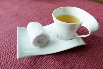white scented rolled wet towel and hot Thai herb tea on to welcome a guest to Thai aroma massage resort spa, Thailand.