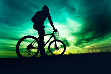 Fototapeta na wymiar Man in helmet and protective gear on mountain bike against sunset sky