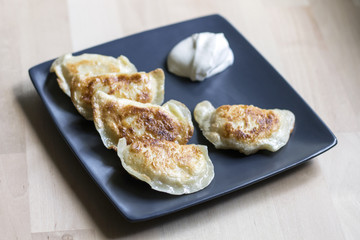 Fried dumplings (called pierogi) with sour cream. Traditional polish food.