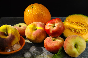 Fresh peaches, melon and orange on ice, hot summer concept