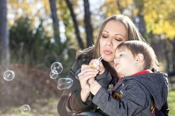 mother blowing soap bubbles to son