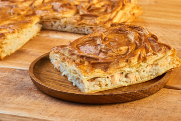 A piece of flaky fish pie with rice in wooden plate