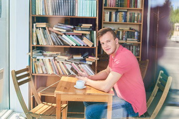 The portrait of the guy with the tablet in hand at a table in a cafe