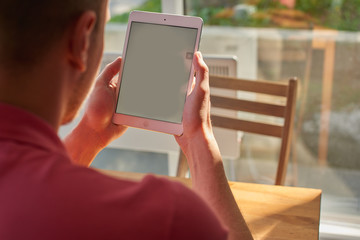 The guy holding the tablet in his hands, sitting at a wooden table