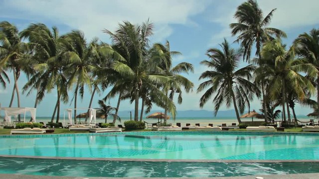 Outdoors lounge zone at the beach. Chill out place among palm trees at the sea. Swimming pool amng coconut palms.