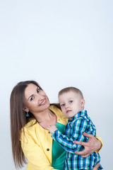 Boy in shirt sitting with mom on light background
