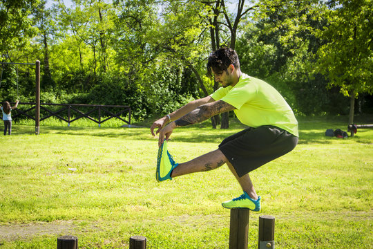 Sportsman balancing in pistol squat on wooden bar