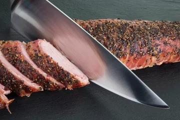 Gardinen Gegrilltes Filetstück auf schwarzer Schieferplatte. Fleischscheiben auf der linken Seite, Fleischmesser schneidet weitere Scheiben. © gani_dteurope