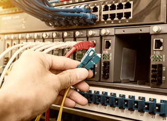 man working in network server room with fiber optic hub for digi