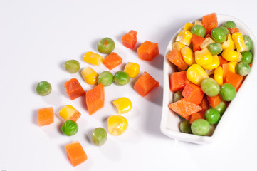 Vegetables three colors carrots kernels peas in spoon white background