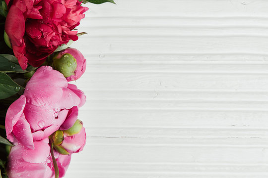 Fototapeta Pink peonies on white wooden table with copy space