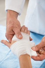 Person Wrapping Bandage To Patient