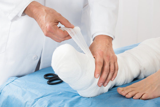 Doctor Tying Bandage On Patient Leg