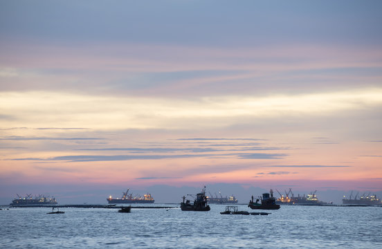 Twiling and sunset at the sea with fishing boat and cargo ship
