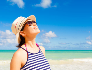 Happy summer days on the beach. Girl looking into the blue sky on a beautiful white sand beach. 