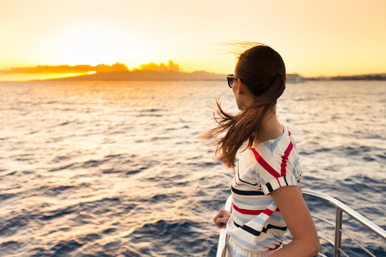 Young woman watching the sunset on a yacht. 