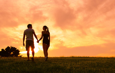 Couple holding hands and walking into the beautiful sunset. 