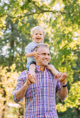 Fototapeta premium Son sitting on his father's neck in the park