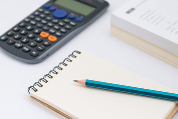 Blank notebook with calculator and pencil on white background