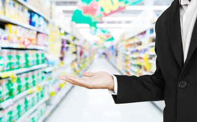 Businessman stretch hand with defocus supermarket aisle background