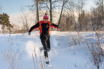 Trail runner in winter forest. Running across the snowy fields