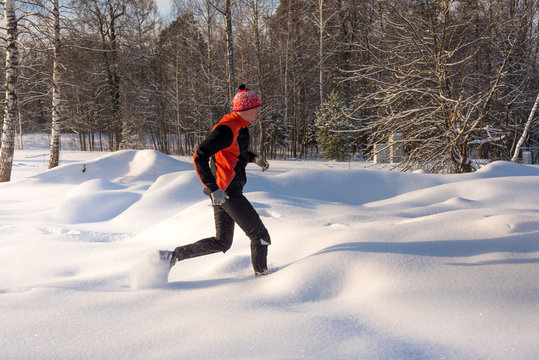 Trail runner in winter forest. Running across the snowy fields