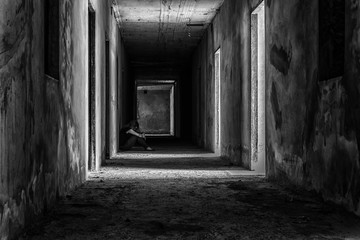 depressed woman sitting on walkway in creepy abandoned building, darkness concept