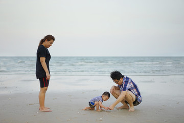 Fototapeta na wymiar Happy Young Asian Family Having Fun Walking on at tropical beach