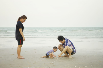 Fototapeta na wymiar Happy Young Asian Family Having Fun on tropical beach vacation o