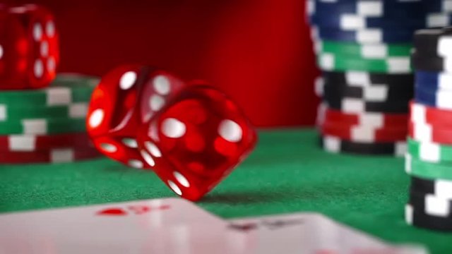 Red dice in sequence rolls, casino chips, cards on green felt