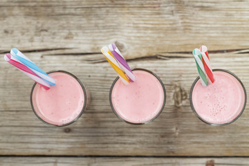 Strawberry smoothies, strawberry detox, strawberry milkshake and non-ferrous tubes on wooden background. Fresh cold strawberry smoothies with fresh fruits