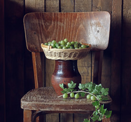 Green gooseberries in a basket on the chair.