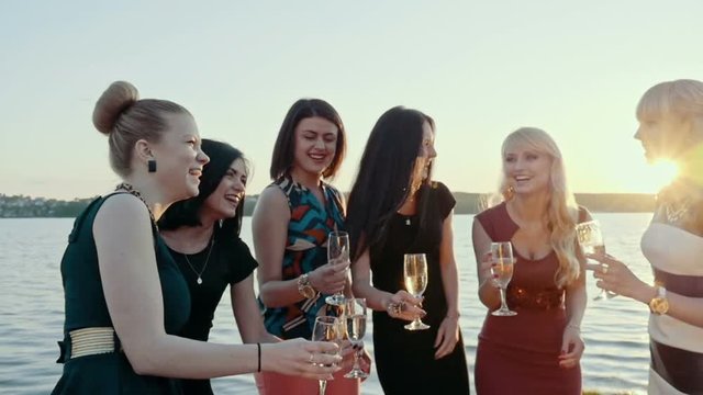 Party, holidays, celebration, nightlife and people concept - smiling friends with glasses of champagne on the beach. Slow motion.