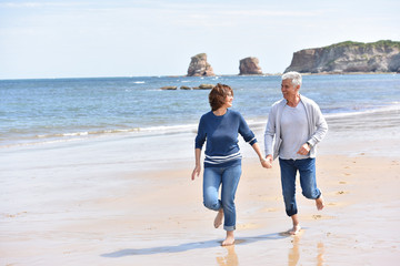 Senior couple running on a sandy beach