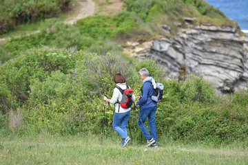Fototapeta na wymiar Senior couple walking on hiking track by the coast