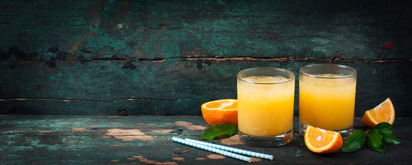 Fresh orange juice with crushed ice and fresh oranges and blue straws on an old vintage exotic...