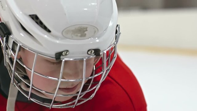 Close up of little boy - hockey player in helmet tilting up his head and looking away