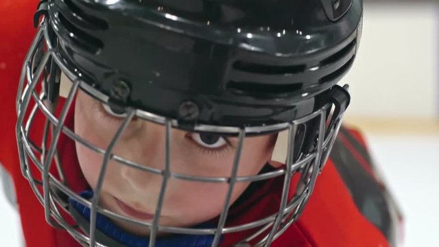 Close up of little hockey player in helmet tilting up his head and looking at the camera