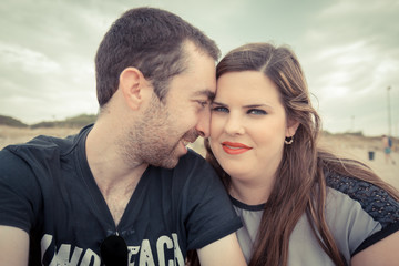 Young couple taking selfie with smartphone or camera at the beac