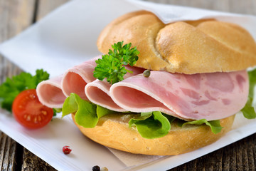 Garniertes Brötchen mit Schinkenwurst auf Pappteller mit Serviette - Roll with sliced ham sausage...