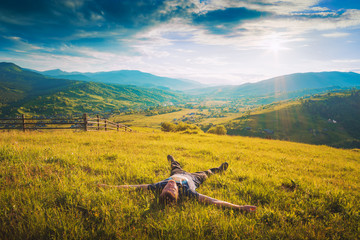 Fototapeta na wymiar Tourist lying on a hill in a fresh green grass