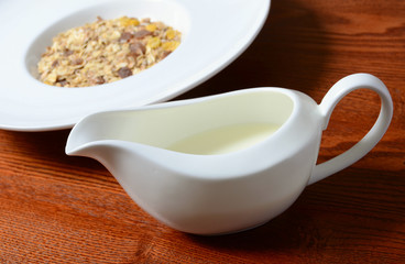 Healthy breakfast background. Bowl of corn flakes with jar of milk on wooden table