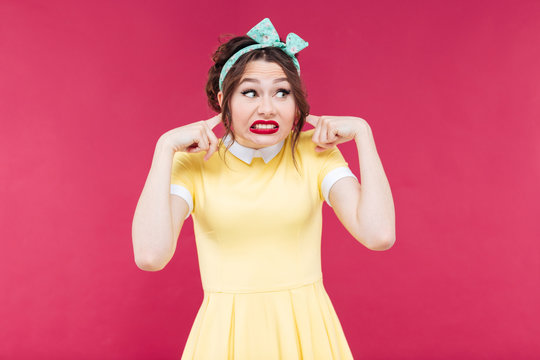 Cute irritated pinup girl closed her ears by fingers
