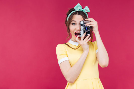 Happy beautiful pinup girl taking photos using vintage camera