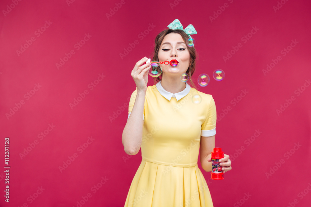 Sticker Attractive pinup girl in yellow dress blowing soap bubbles