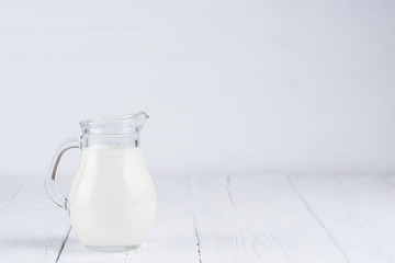 Jug of milk on white wooden table still life
