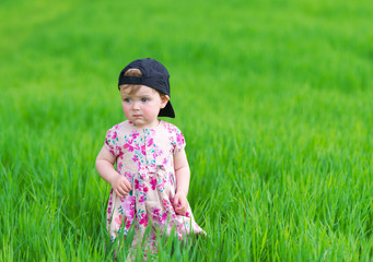 Portrait of the little girl against green grass.