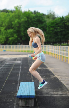 The Beautiful Sportswoman Jumps On A Bench Up.