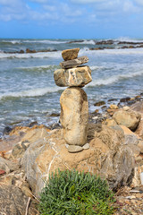 Fototapeta na wymiar Rock balancing over a cliff on a shore near the rough sea