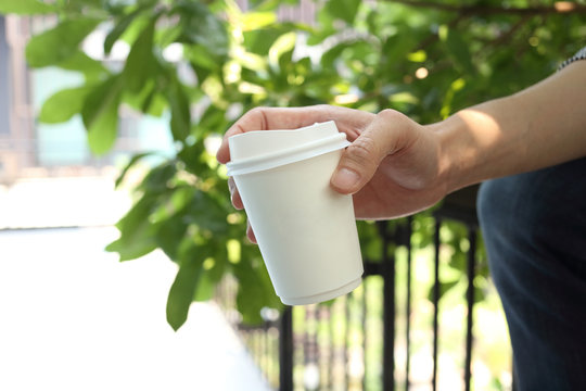 Hand Holding Paper Coffee Cup With Office Background